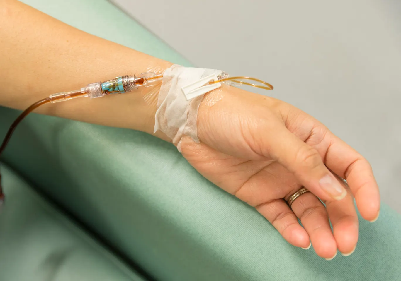 Kroplówki witaminowe Płock: dłoń z wenflonem i linią infuzyjną na podkładzie
